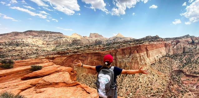 lady standing with outstretched arms, at top of mountain