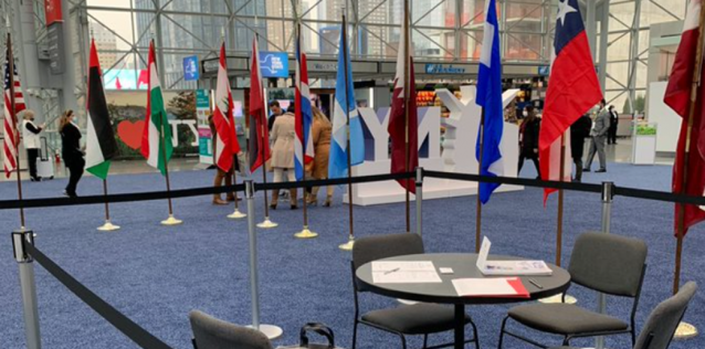 People mingling on a trade show floor among international flags