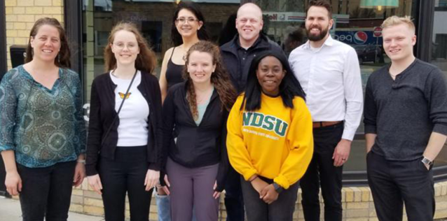 Group of eight people standing in front of a restaurant