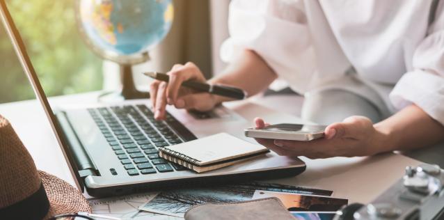 Image focused on desk with a person sitting using a laptop.