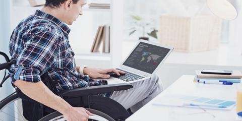 Man sitting in wheelchair studies his laptop.