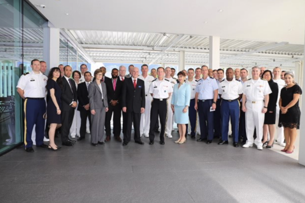 A group of military people posing for a picture outside of the office wide-angle shot