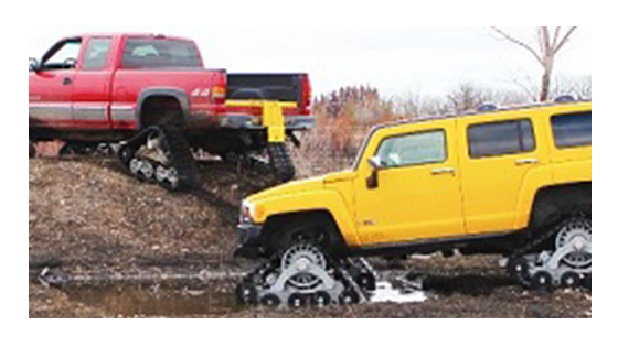 Two trucks using mattracks to get up muddy road