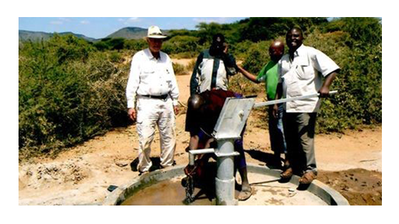 Four men standing near a water well