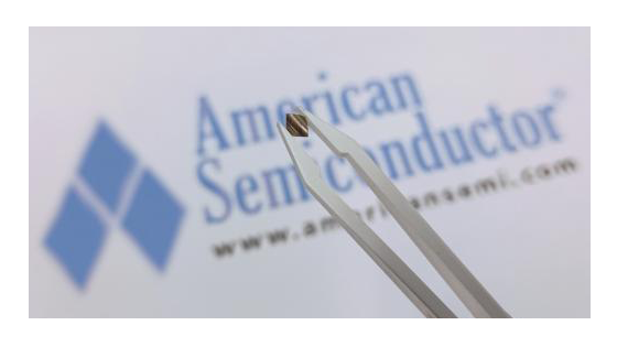 A tweezer holding a small chip in front of the logo of American Semiconductor