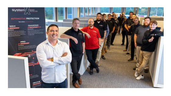A team of around 20 people standing in an office
