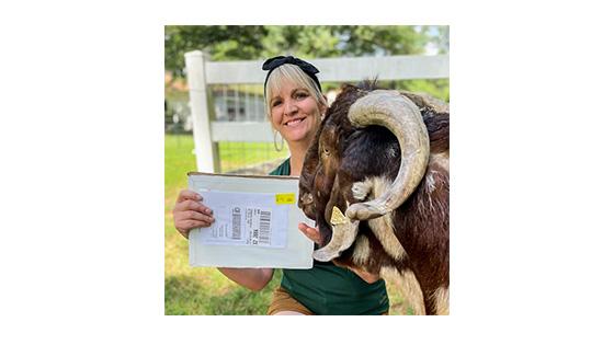 Woman holding health certificate for first sale alongside a boer goat buck