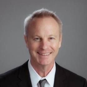 Bust photo of Greg Sizemore wearing a black blazer, white collared shirt, and grey tie