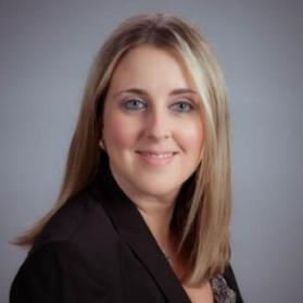 Bust photo of Stephanie Bethel with a gray backdrop, black blazer and patterned blouse.