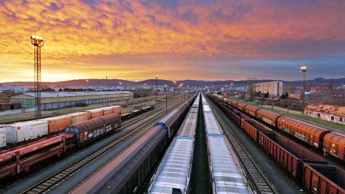 A freight rail yard with a sunset sky overhead