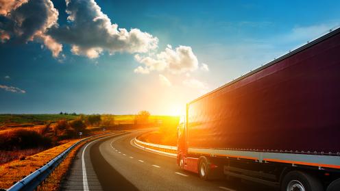 A truck drives on the highway towards the horizon.